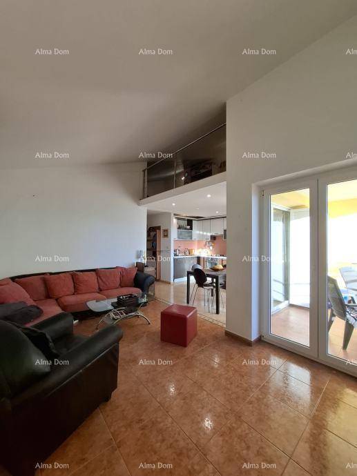 Offener Wohn- und Essbereich mit Fliesenboden, rotem Sofa und Zugang zu einem Balkon.