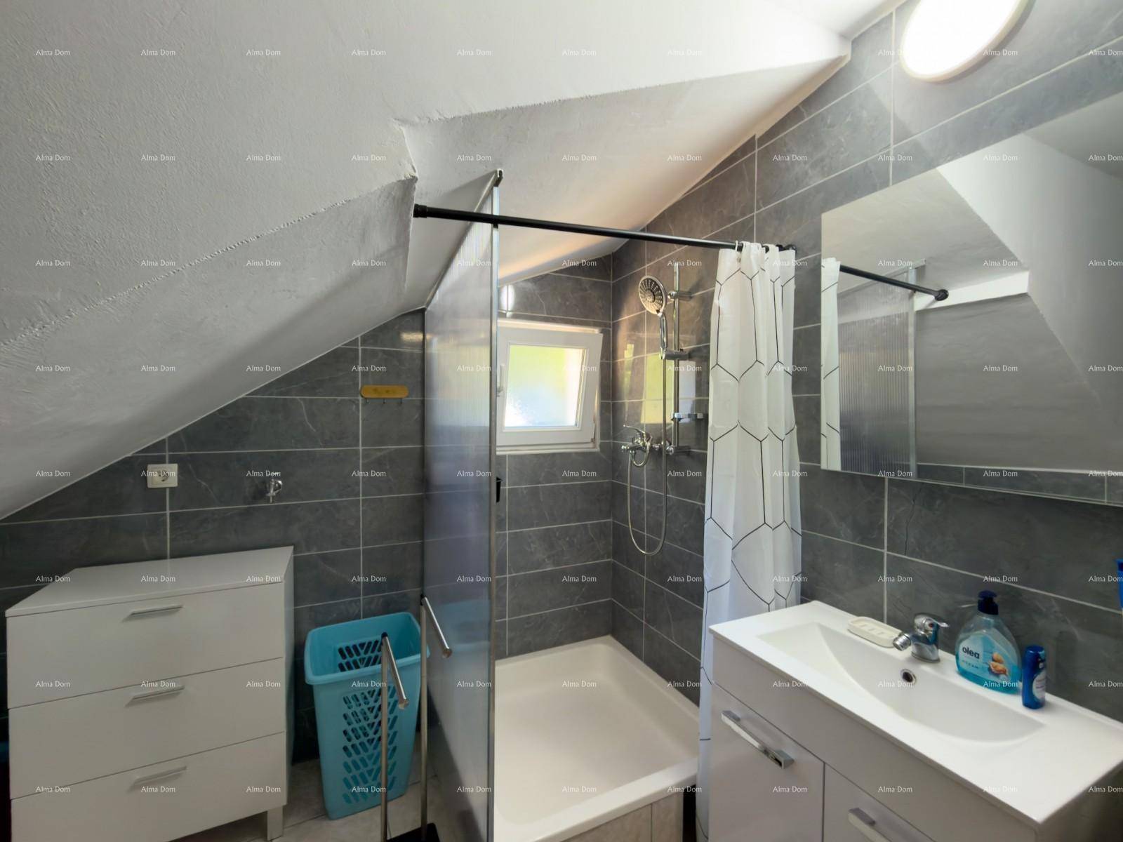 Modernes Badezimmer mit grauen Fliesen, Duschwanne und Fenster unter Dachschräge.