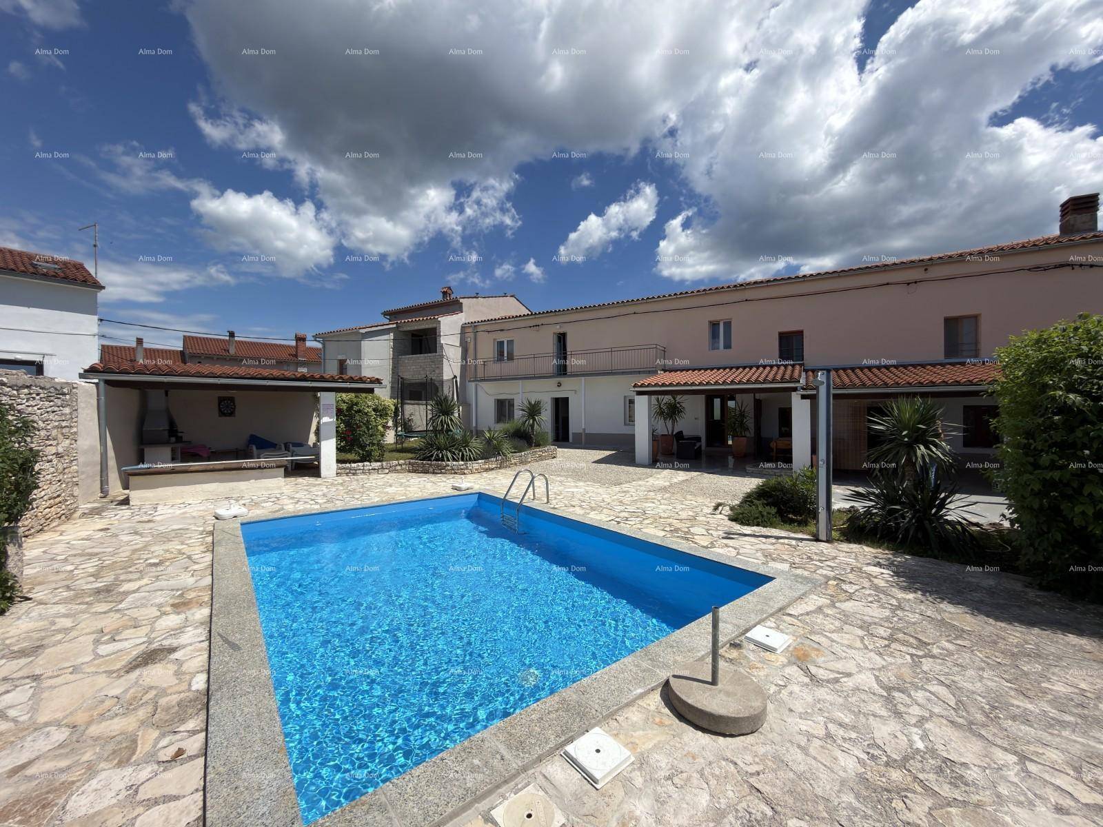 Großer Außenbereich mit Swimmingpool und gepflasterter Terrasse unter blauem Himmel.