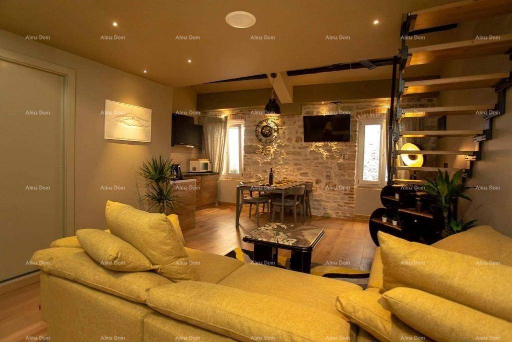 Gemütlicher Wohn- und Essbereich mit gelbem Sofa, Esstisch und rustikaler Steinwand, verbunden durch eine offene Treppe.