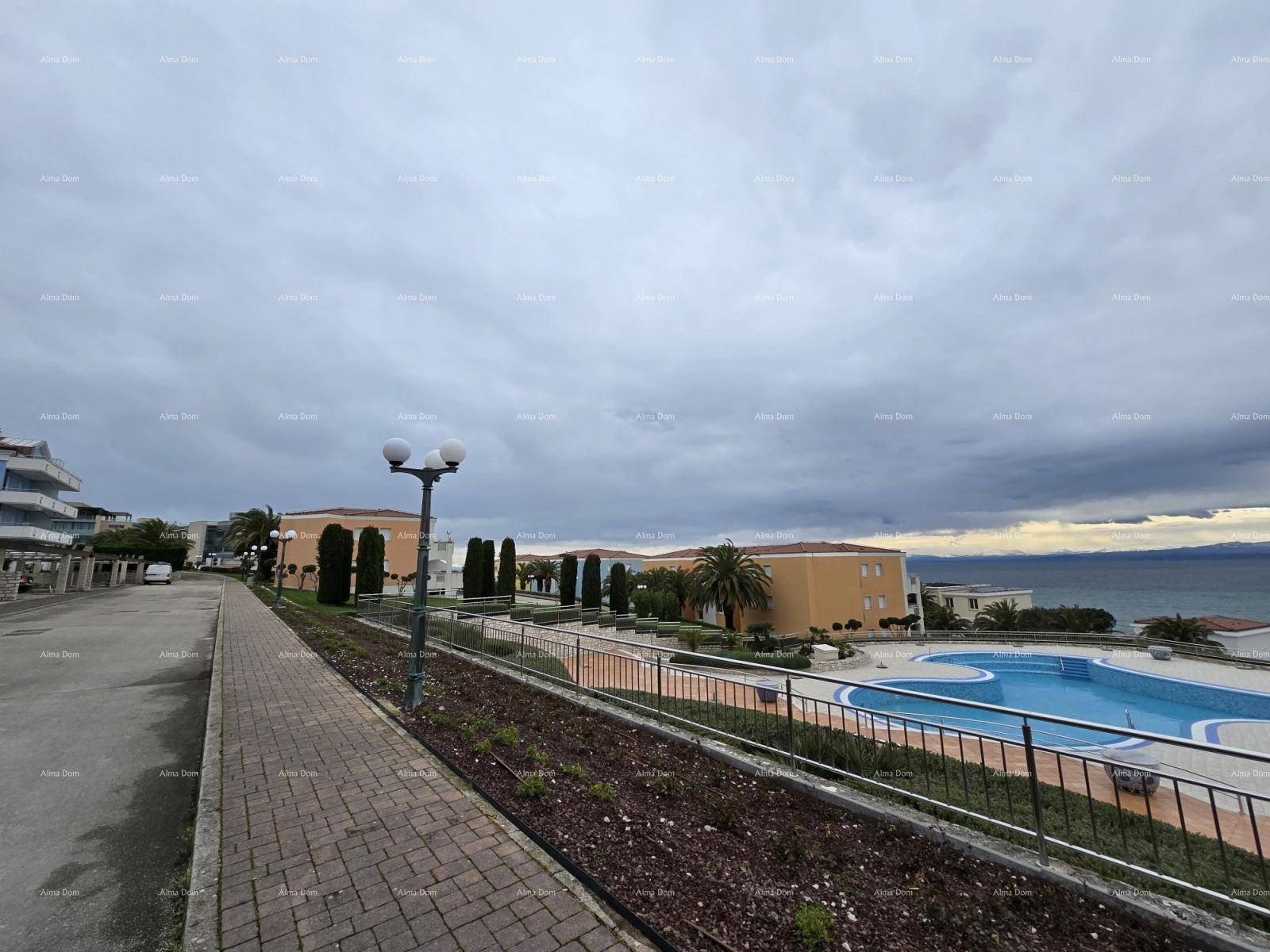 Außenansicht der Wohnanlage mit Straße, Poolbereich und weitem Blick auf das Meer.