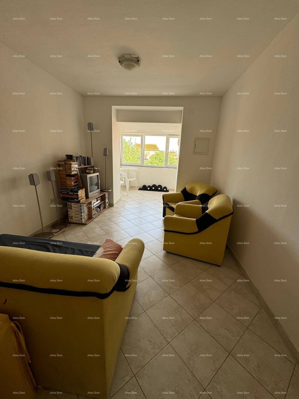 Gemütliches Wohnzimmer mit gelben Sofas, Fliesenboden und einem Fenster, das Tageslicht hereinlässt.