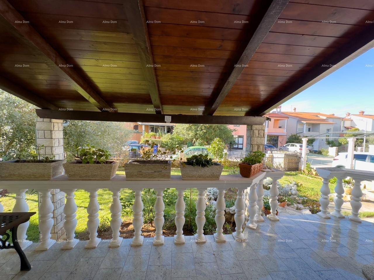 Überdachte Terrasse mit Balustrade und Blick auf den Vorgarten und die Umgebung.