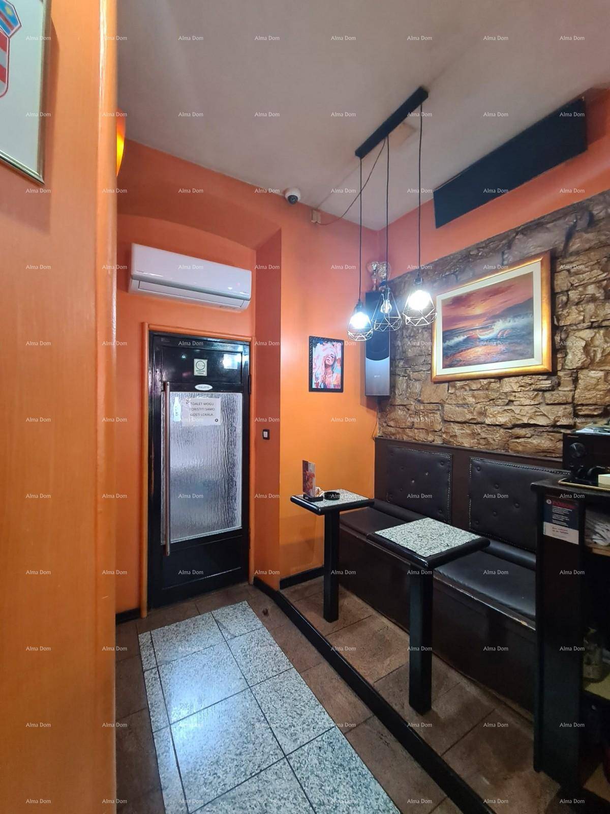 Sitzbereich in einer Bar mit gepolsterten Bänken, kleinen Tischen und einer Klimaanlage an der Wand.
