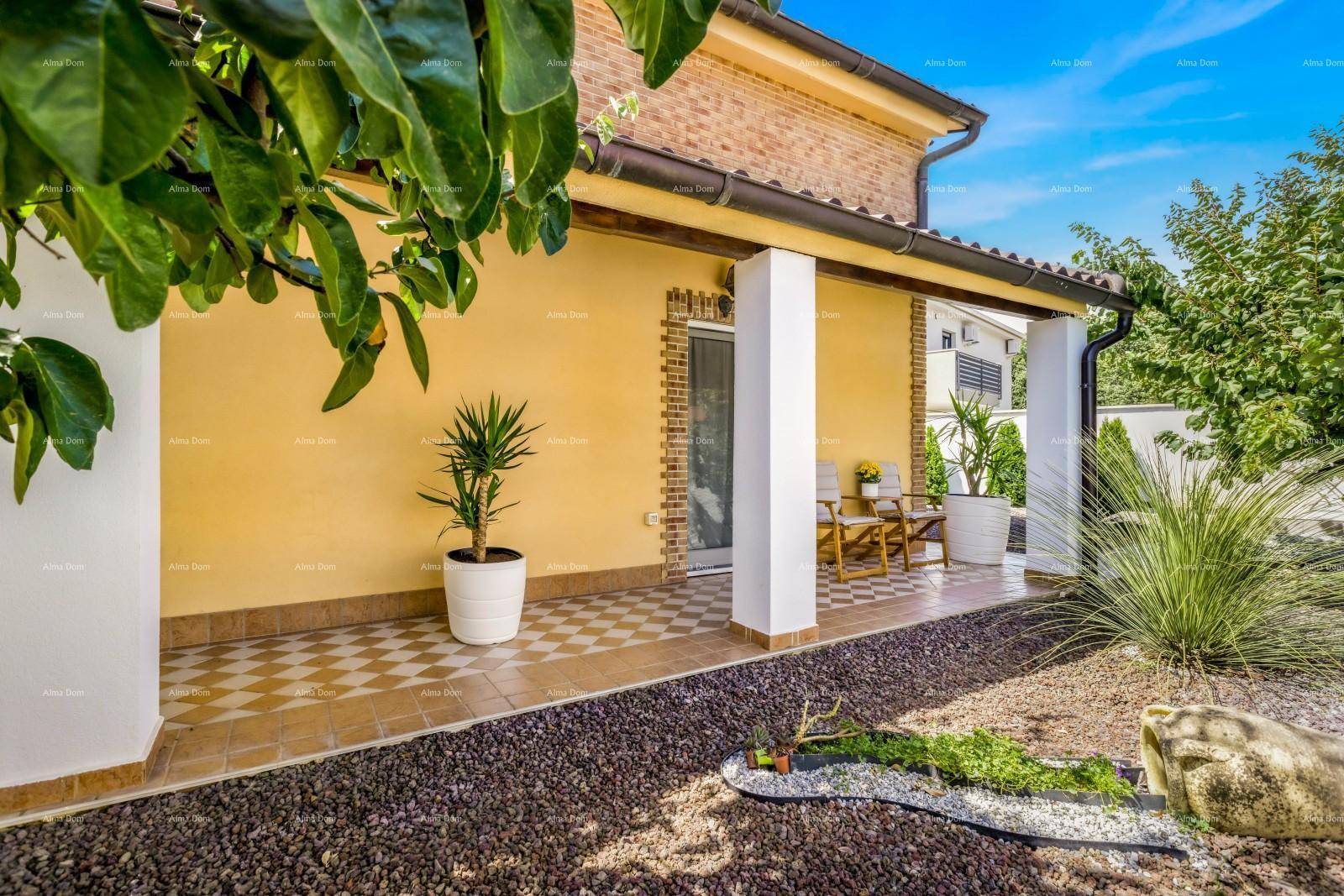 Seitlicher Blick auf das Haus mit überdachter Terrasse, Kiesbeet und mediterraner Bepflanzung.