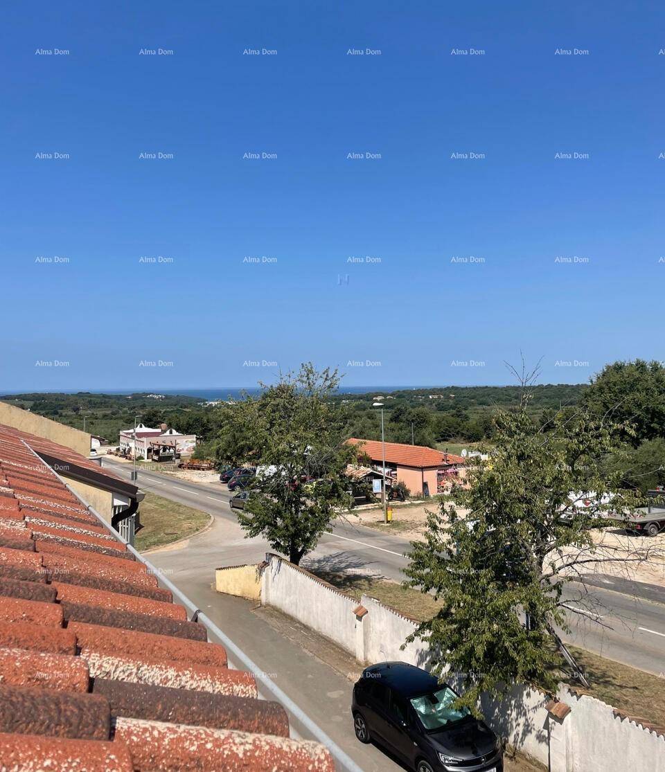 Panoramablick über eine Straße mit Bäumen und Häusern, im Hintergrund ist das Meer zu sehen.