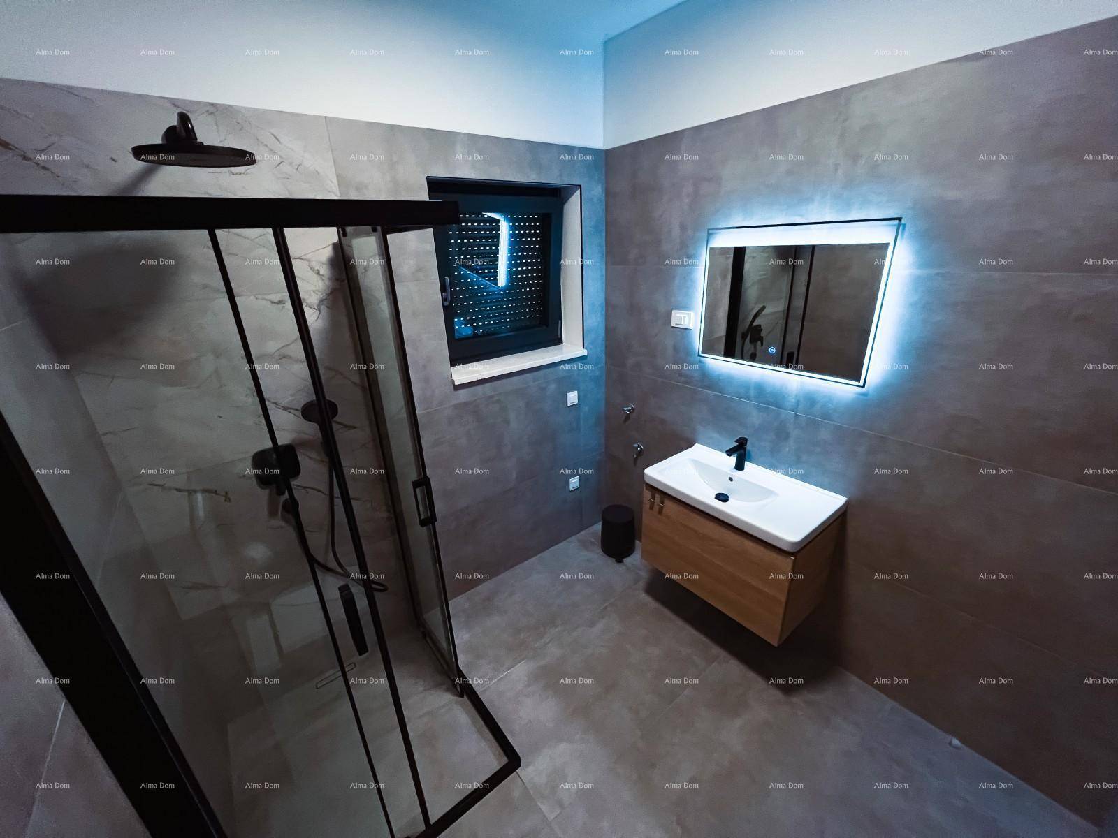 Modernes Badezimmer mit großer Duschkabine, beleuchtetem Spiegel und stilvollen grauen Fliesen, die eine ruhige Atmosphäre schaffen.