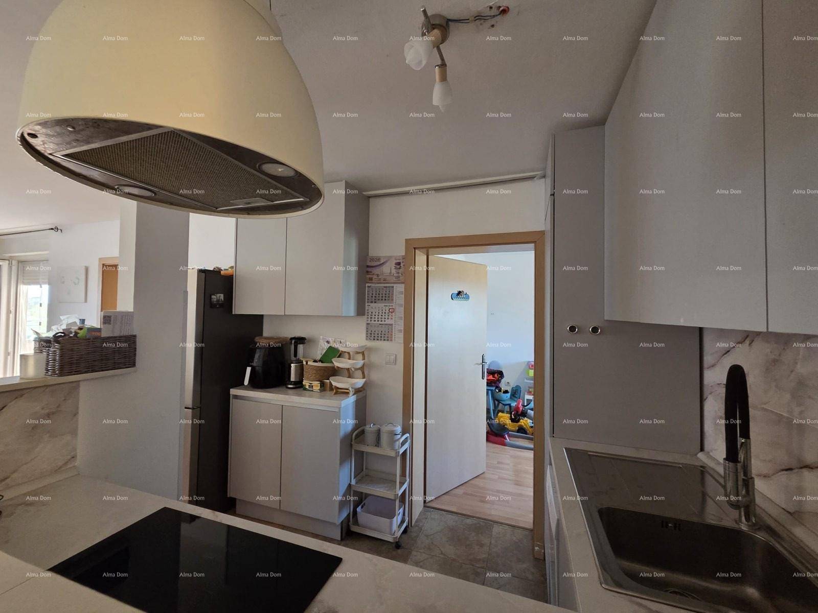 Moderne Küche mit hellen Schränken, Induktionskochfeld und Dunstabzugshaube.