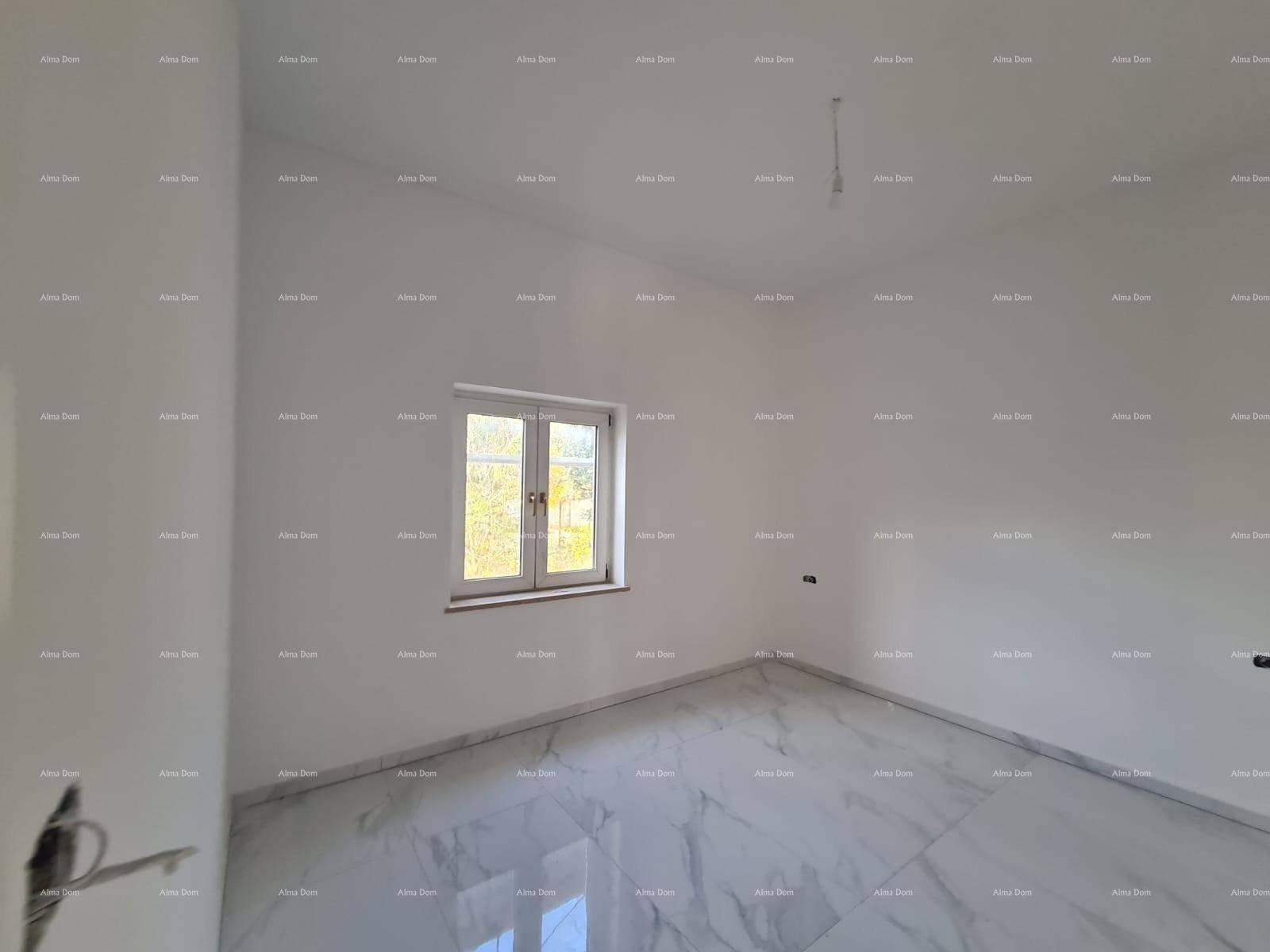 Helles Schlafzimmer im Rohbau mit Marmorboden und einem Fenster, das viel Tageslicht hereinlässt.