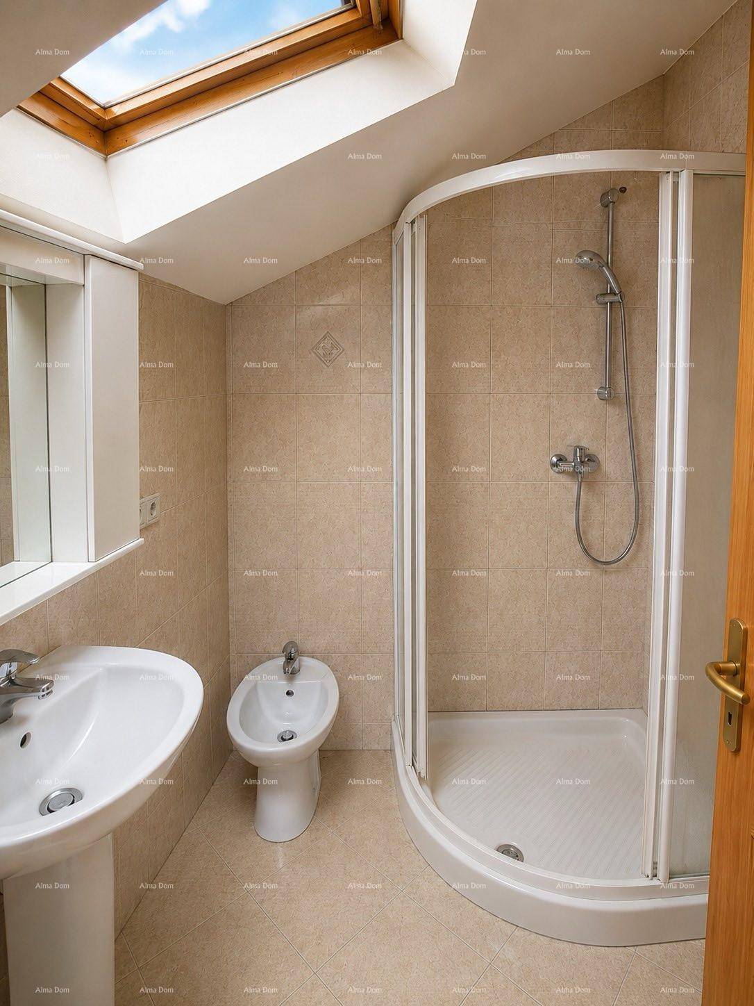 Helles Badezimmer im Dachgeschoss mit Duschkabine, Bidet und viel Tageslicht durch das Dachfenster.