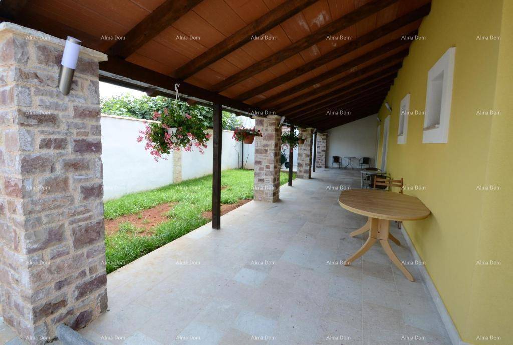 Lange überdachte Terrasse mit Steinpfeilern und Blick auf den Garten.