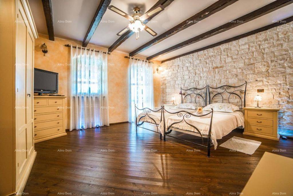 Geräumiges Schlafzimmer mit Holzboden, sichtbaren Deckenbalken und einer rustikalen Steinwand.