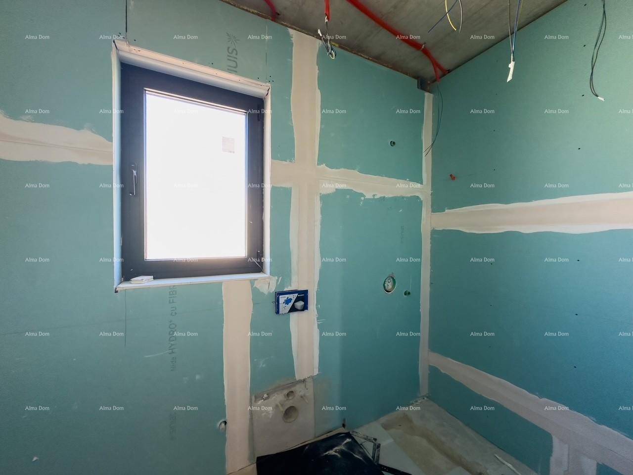 Badezimmer im Rohbau mit blauen Trockenbauwänden, Fenster und vorbereiteten Anschlüssen für die Sanitäreinrichtung.
