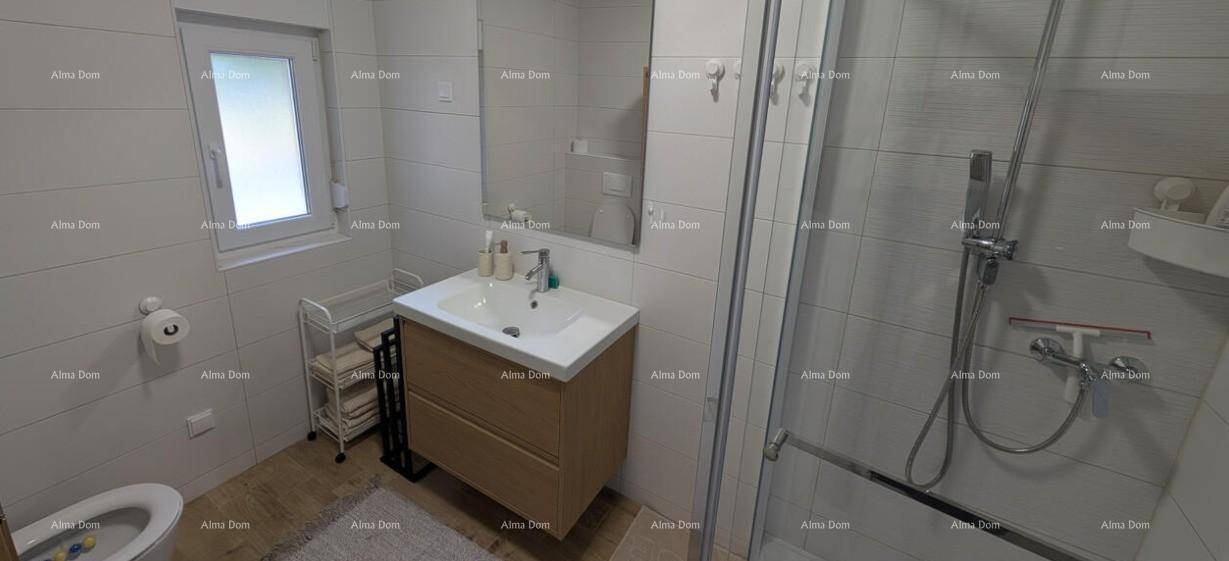 Helles Badezimmer mit Toilette, Waschbecken, Spiegel und begehbarer Dusche am Fenster.
