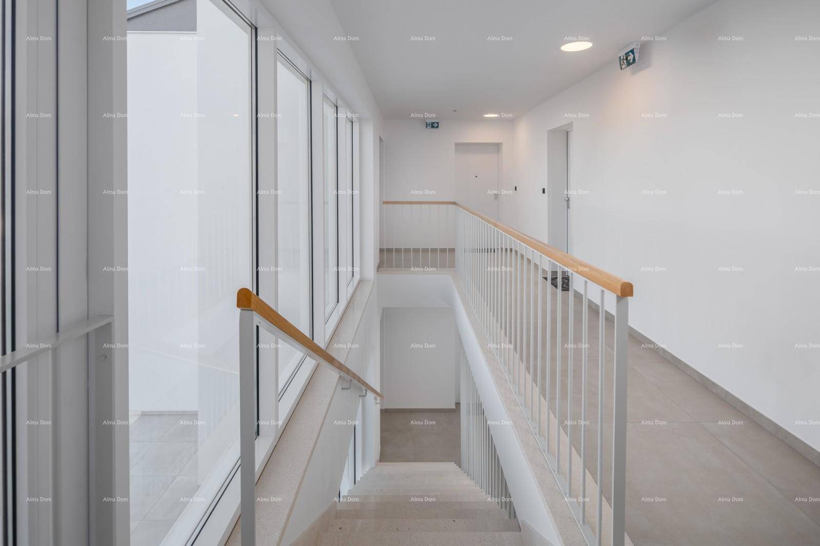 Heller Treppenaufgang mit Rampe und großen Fenstern, die viel Licht hereinlassen und Barrierefreiheit bieten.