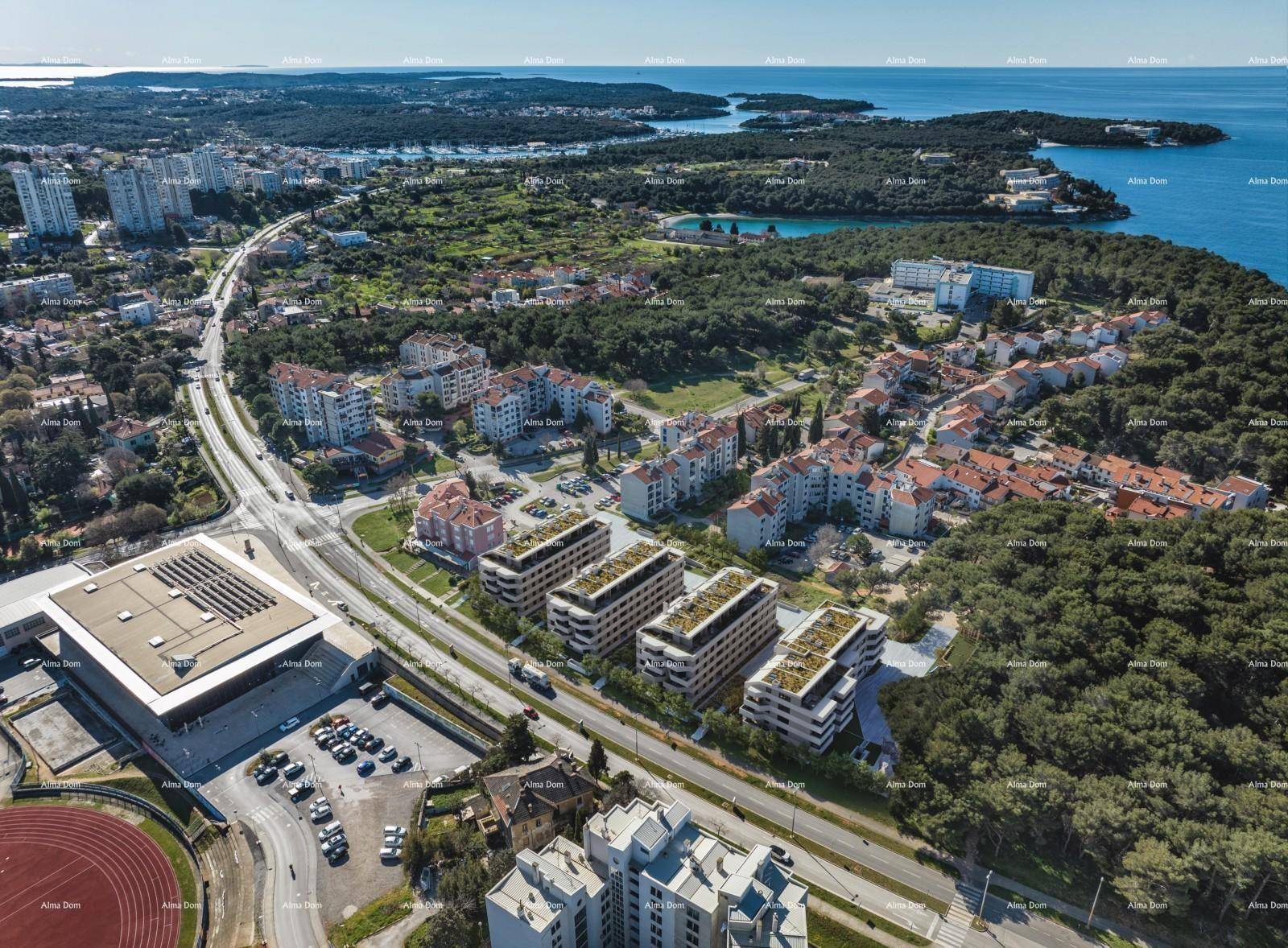 Weitläufige Luftaufnahme der modernen Wohnanlage mit Blick auf die Stadt, das Stadion und die Küste.