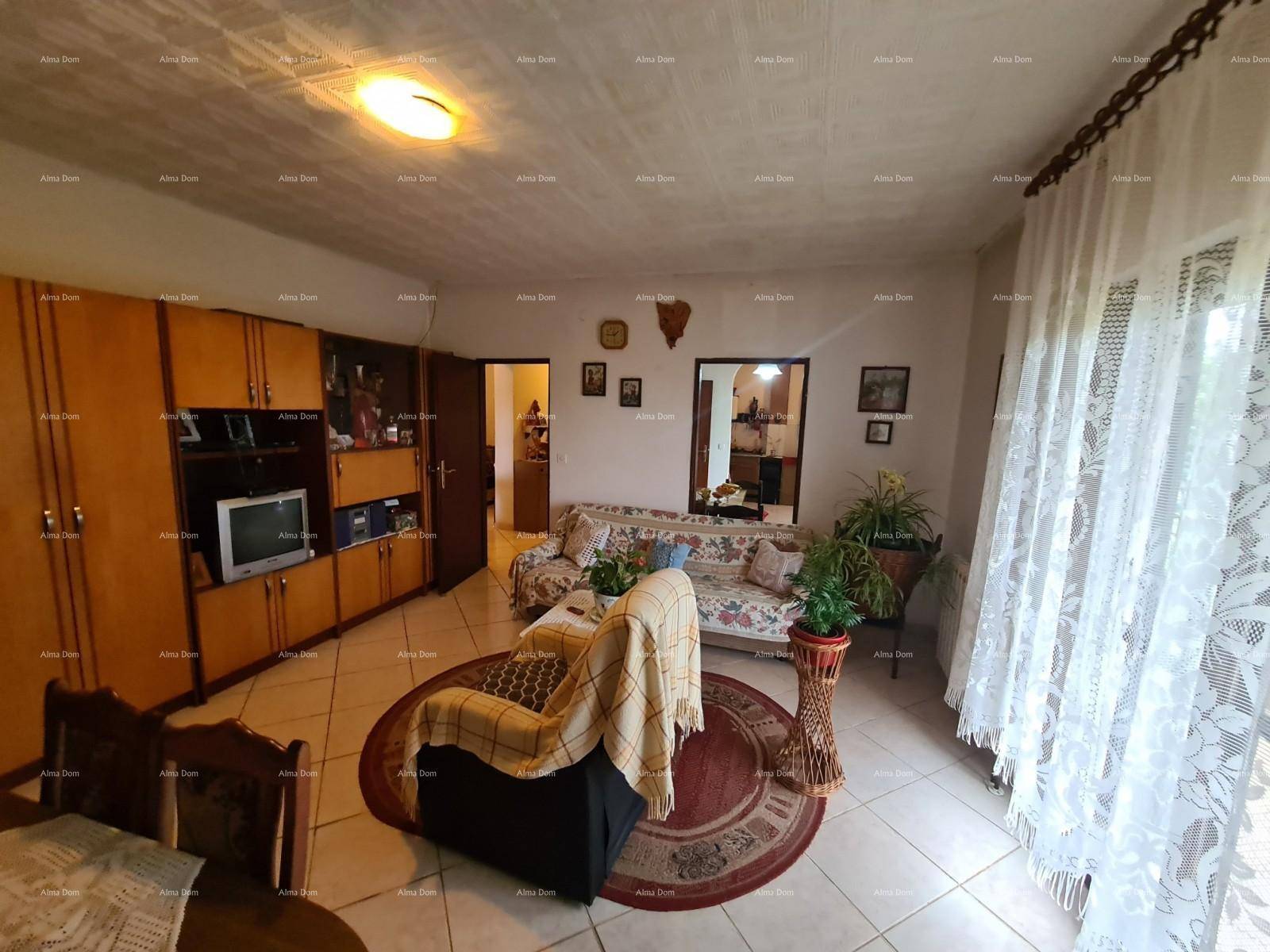 Heller Wohn- und Essbereich mit Holzschränken, Sofa und Zugang zum Balkon durch große Fenster.