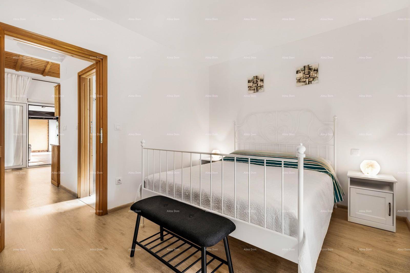 Helles Schlafzimmer mit weißem Metallbett, Holzboden und Zugang zu einem weiteren Raum.