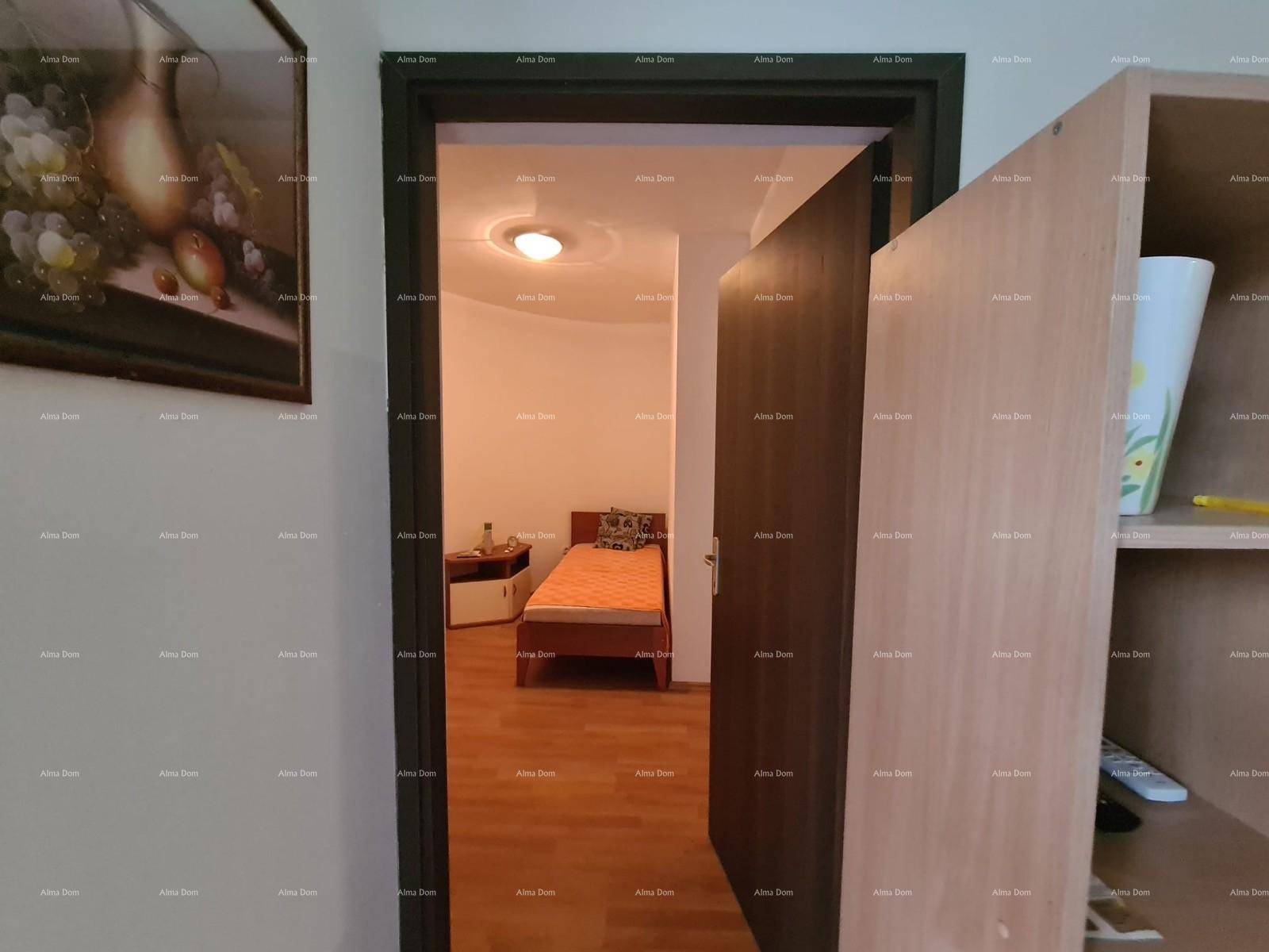 Schlafzimmer mit Einzelbett und heller Beleuchtung, sichtbar durch eine offene Tür.