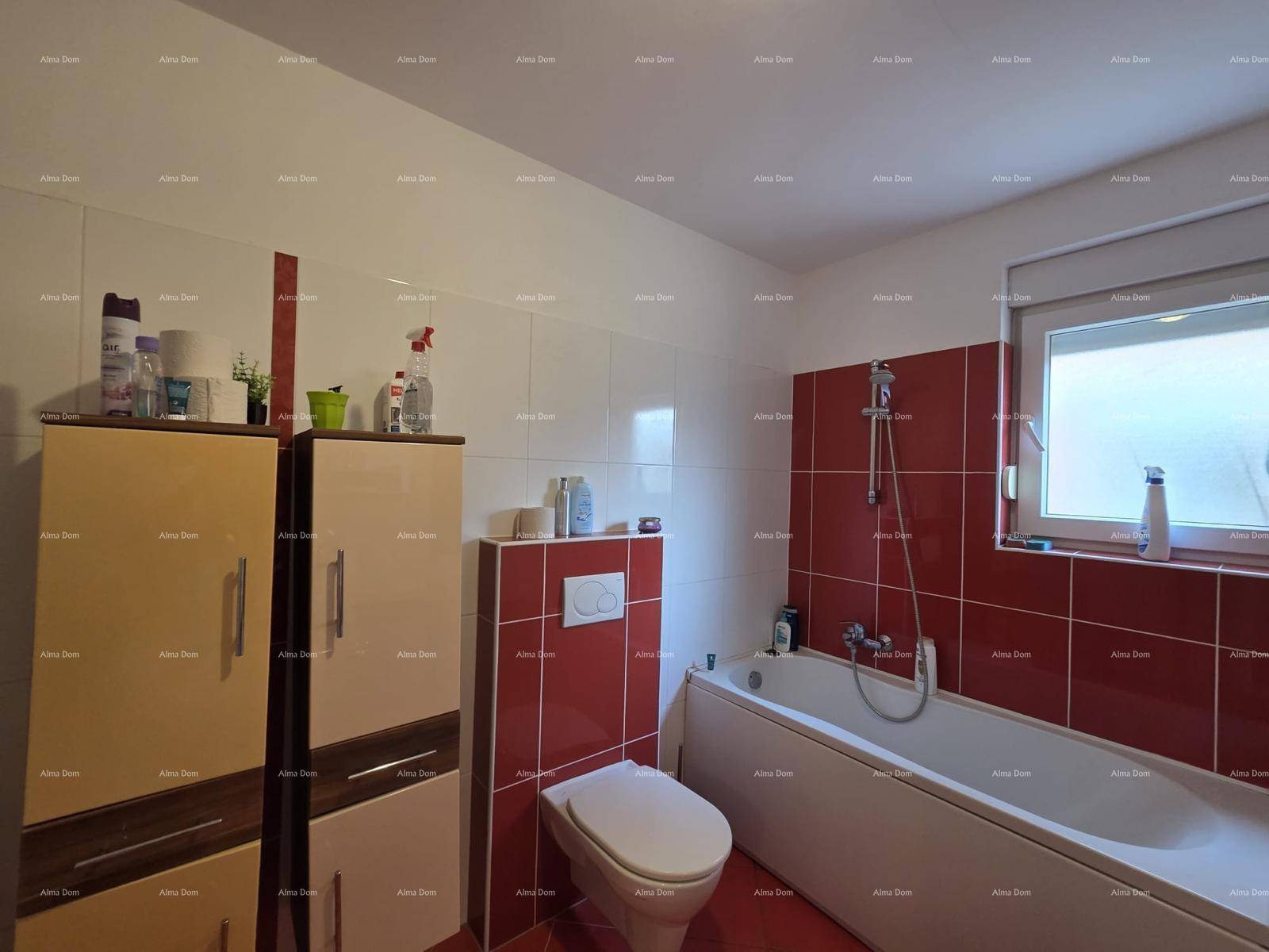 Badezimmer mit Badewanne, Wand-WC und roten Fliesen, die einen Farbakzent setzen.