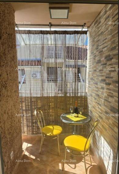 Überdachter Balkon mit Steinwandverkleidung, kleinem Tisch und zwei gelben Stühlen.