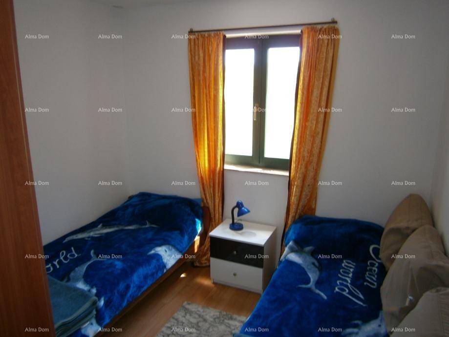 Schlafzimmer mit zwei Einzelbetten, Holzboden und Fenster mit Vorhängen.