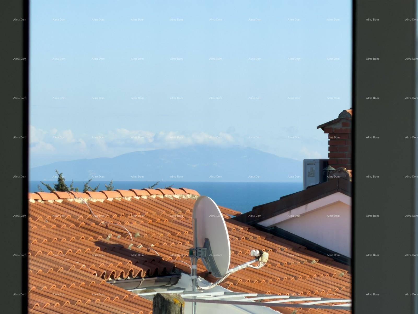 Blick aus dem Fenster über rote Dächer auf das Meer und ferne Berge am Horizont.