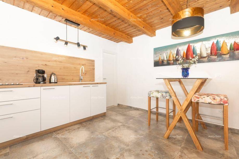 Moderne Küche mit weißen Schränken, Holzarbeitsplatte und Frühstücksbar unter Holzbalkendecke.