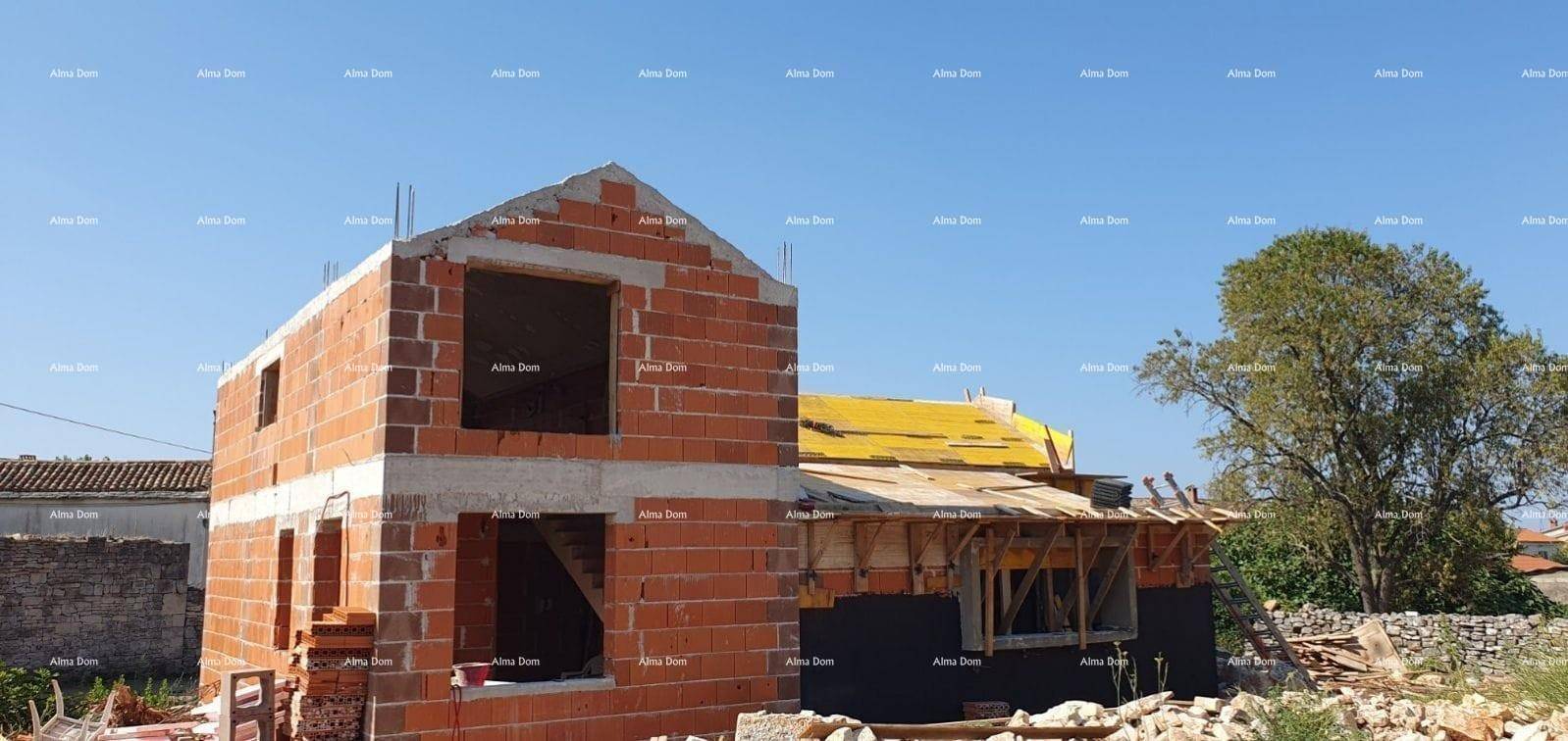 Haus im Rohbau mit Ziegelwänden und sichtbarer Holzkonstruktion unter blauem Himmel.