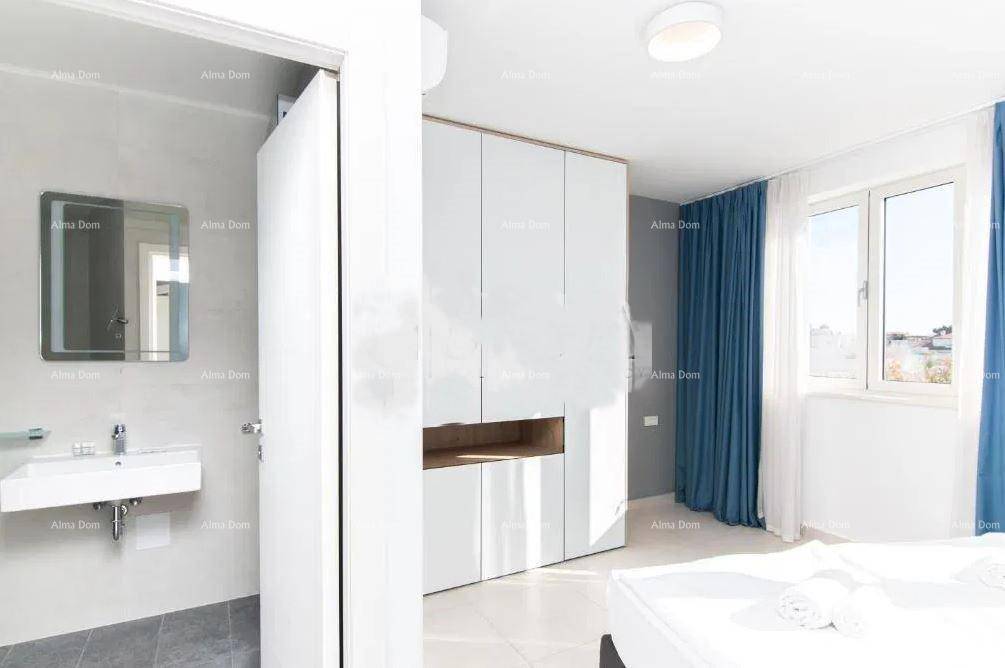 Schlafzimmer mit weißem Einbauschrank und angrenzendem Badezimmerbereich mit Waschbecken.