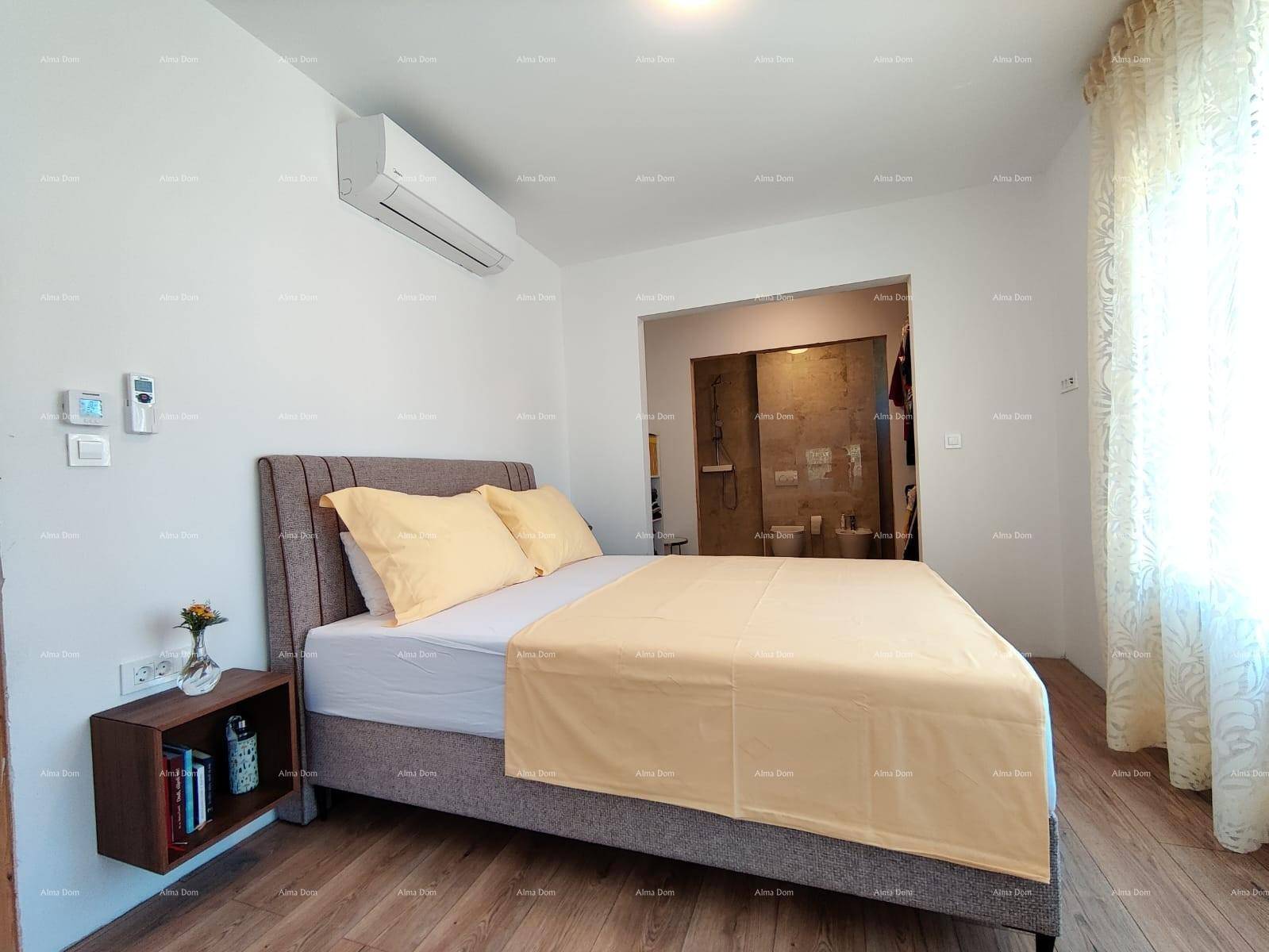 Schlafzimmer mit Holzboden, großem Bett und offenem Zugang zu einem Ankleidebereich.