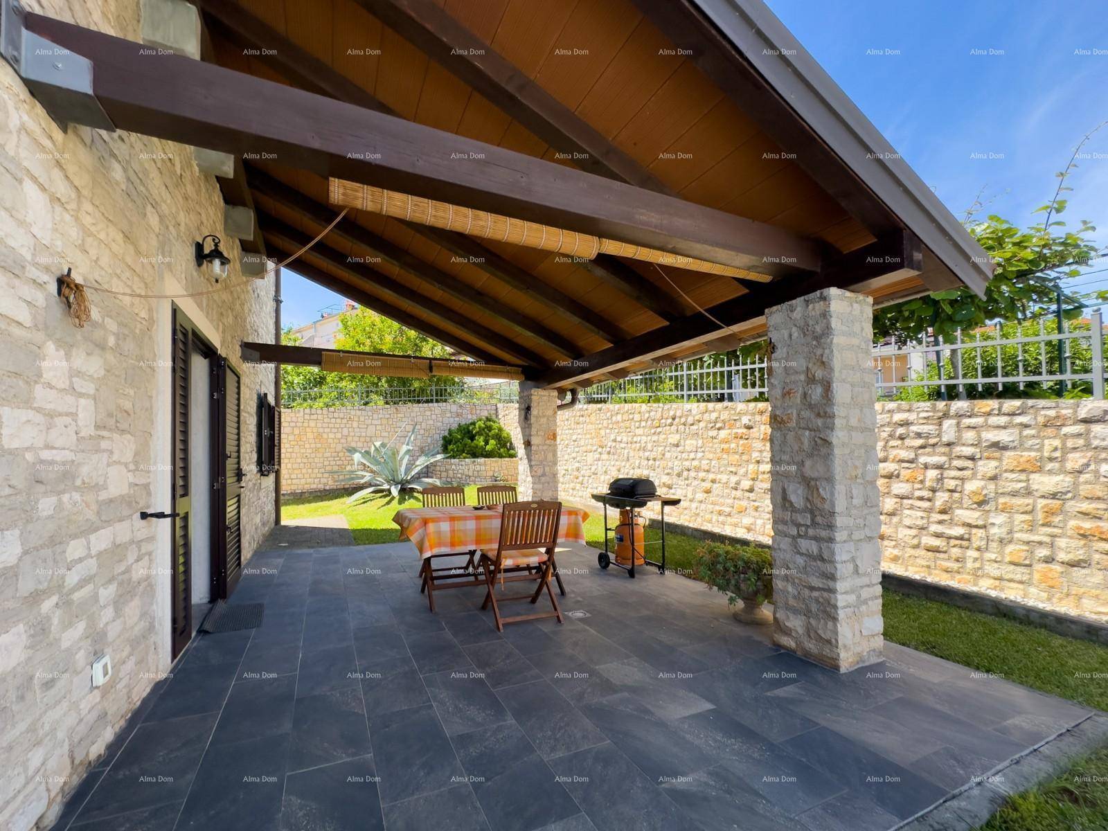 Überdachter Terrassenbereich mit Esstisch, Stühlen und Grill, umgeben von Steinmauern und Fliesenboden.