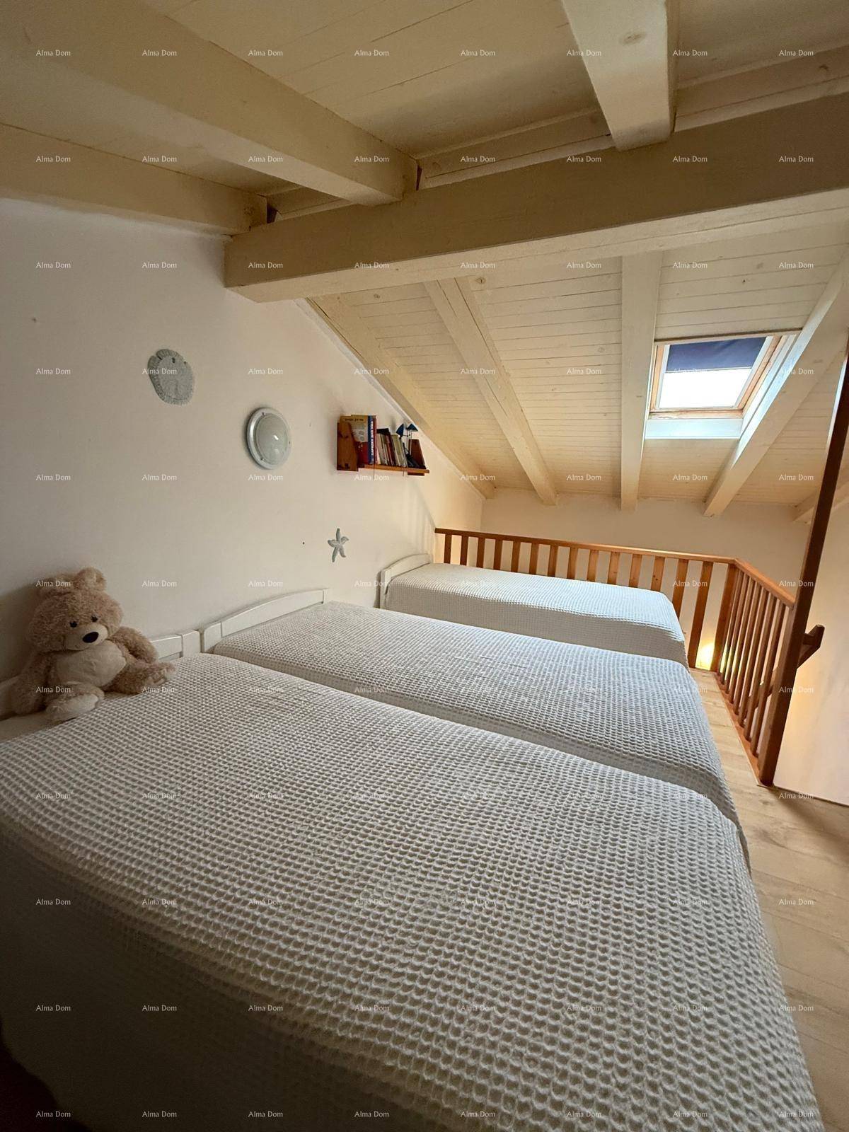 Helles Dachgeschoss-Schlafzimmer mit mehreren Betten, Holzbalkendecke und Dachfenster.