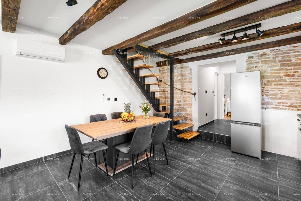 Essbereich mit Holztisch und modernen Stühlen, ergänzt durch eine offene Treppe und eine Klimaanlage.