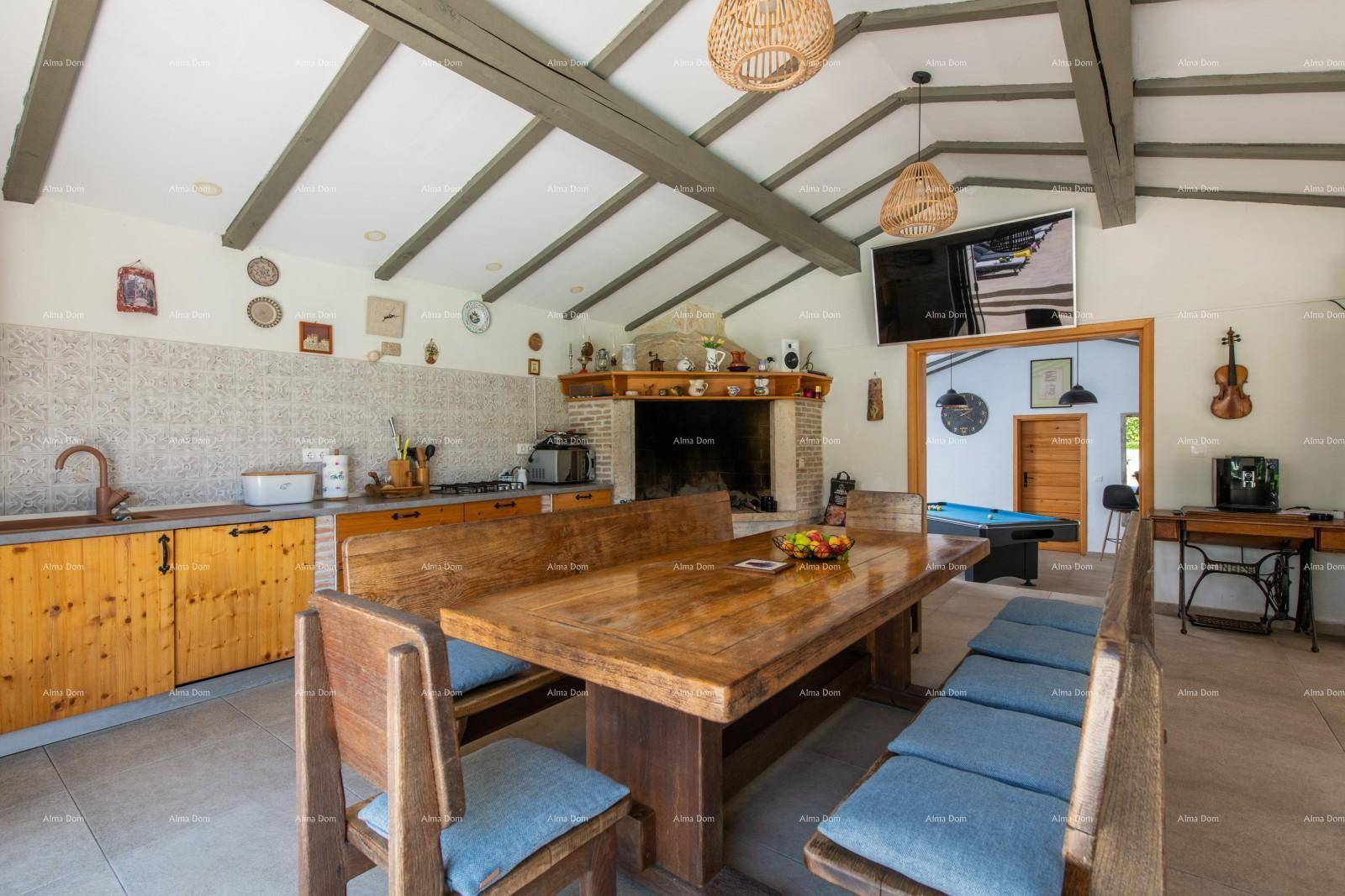 Rustikale Wohnküche mit Holztisch, Kamin und freiliegenden Deckenbalken, angrenzend an einen Spielbereich.