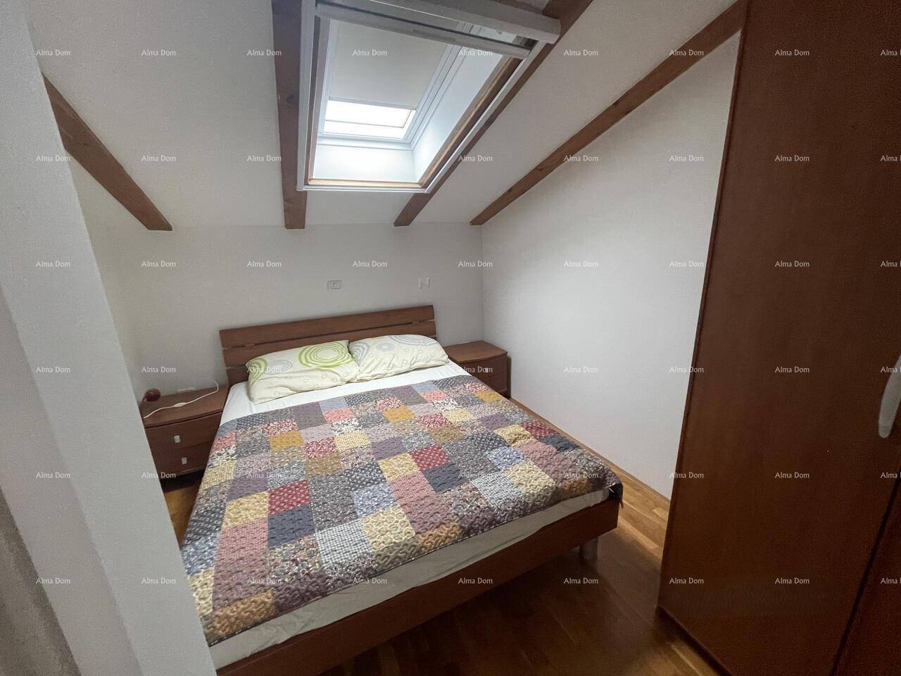 Schlafzimmer im Dachgeschoss mit Doppelbett, Holzfußboden, Dachschräge und einem praktischen Dachfenster.