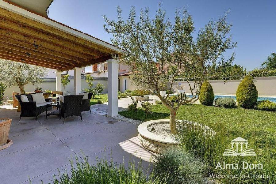 Überdachte Terrasse mit gemütlicher Lounge-Möblierung und Blick auf den grünen Garten.
