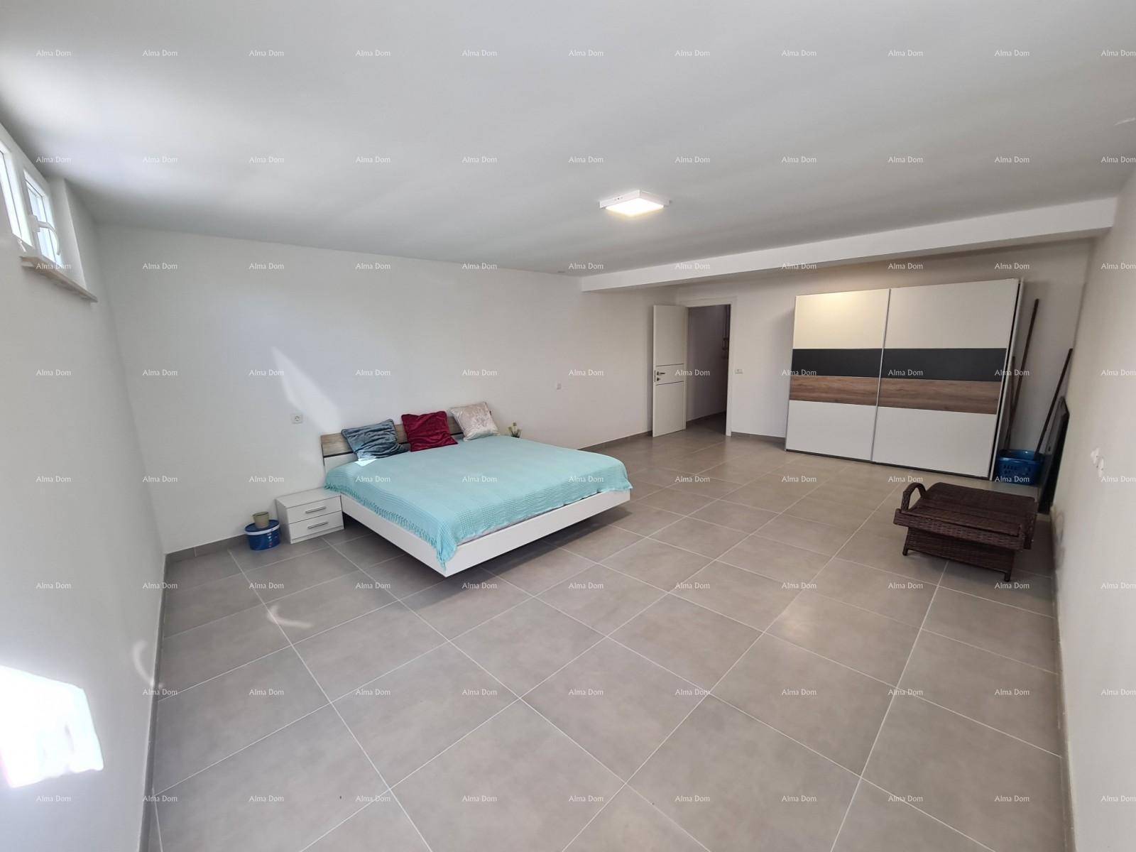 Großer, heller Kellerraum mit Bett, Kleiderschrank und Fliesenboden.