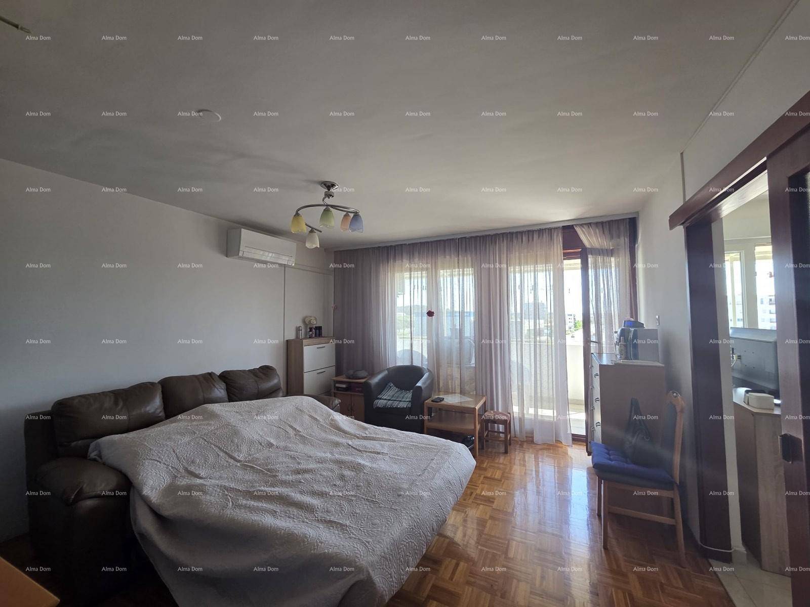 Helles Wohnzimmer mit Parkettboden, Sofa und Zugang zu einem Balkon durch große Fenster.