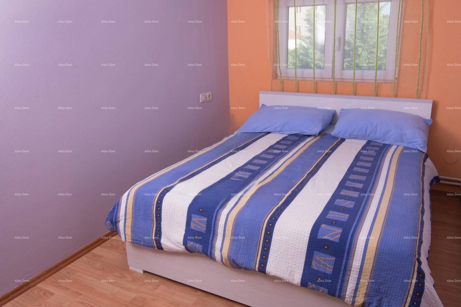 Schlafzimmer mit Doppelbett, Holzboden und farbigen Wänden in Lila und Orange.