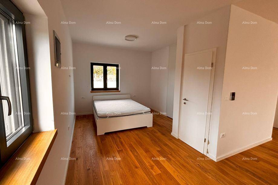 Schlafzimmer mit Holzboden, weißem Bettrahmen und Fenster mit Blick ins Grüne.