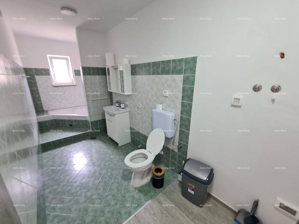 Geräumiges Badezimmer mit grünen Fliesen, Toilette, Waschbecken und einer Eckbadewanne.