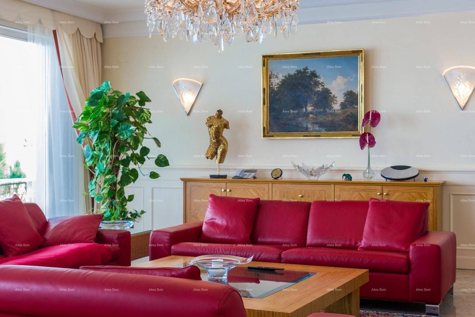 Helles Wohnzimmer mit roten Ledersofas, Kronleuchter und Kunstwerken an den Wänden.
