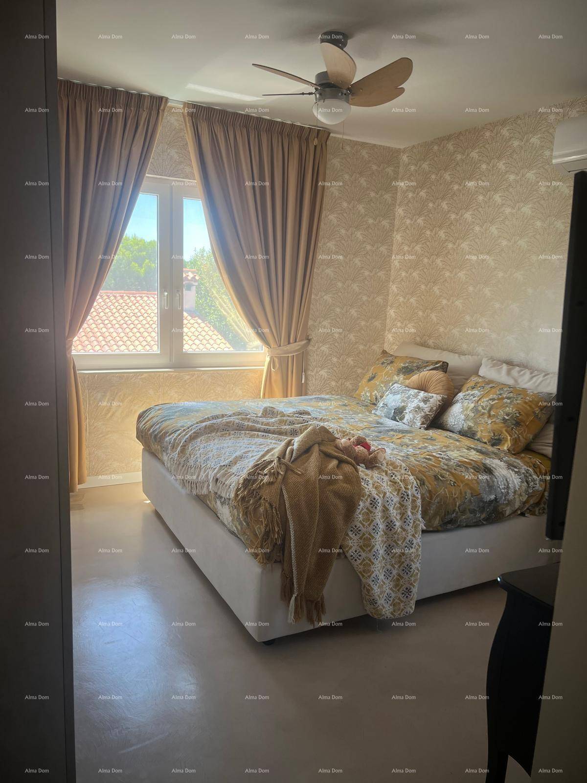 Helles Schlafzimmer mit Doppelbett, gemusterter Tapete, Deckenventilator und Klimaanlage für Komfort.