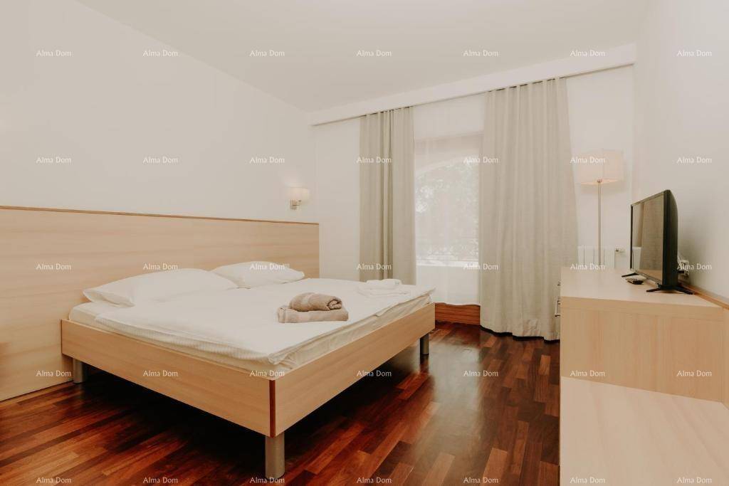 Geräumiges Schlafzimmer mit Doppelbett, Holzboden und Fernseher, bietet Komfort und eine angenehme Atmosphäre.