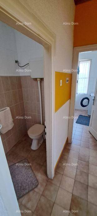 Separate Toilette mit Fliesenboden und gelben Akzentwänden.