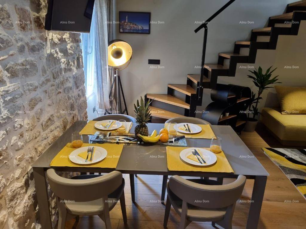 Nahaufnahme des gedeckten Esstisches mit frischen Früchten, im Hintergrund der helle Wohnbereich mit Sofa.