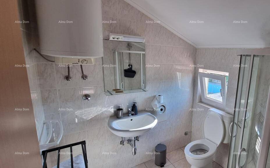 Gefliestes Badezimmer im Dachgeschoss mit Waschbecken, Toilette und Duschkabine.
