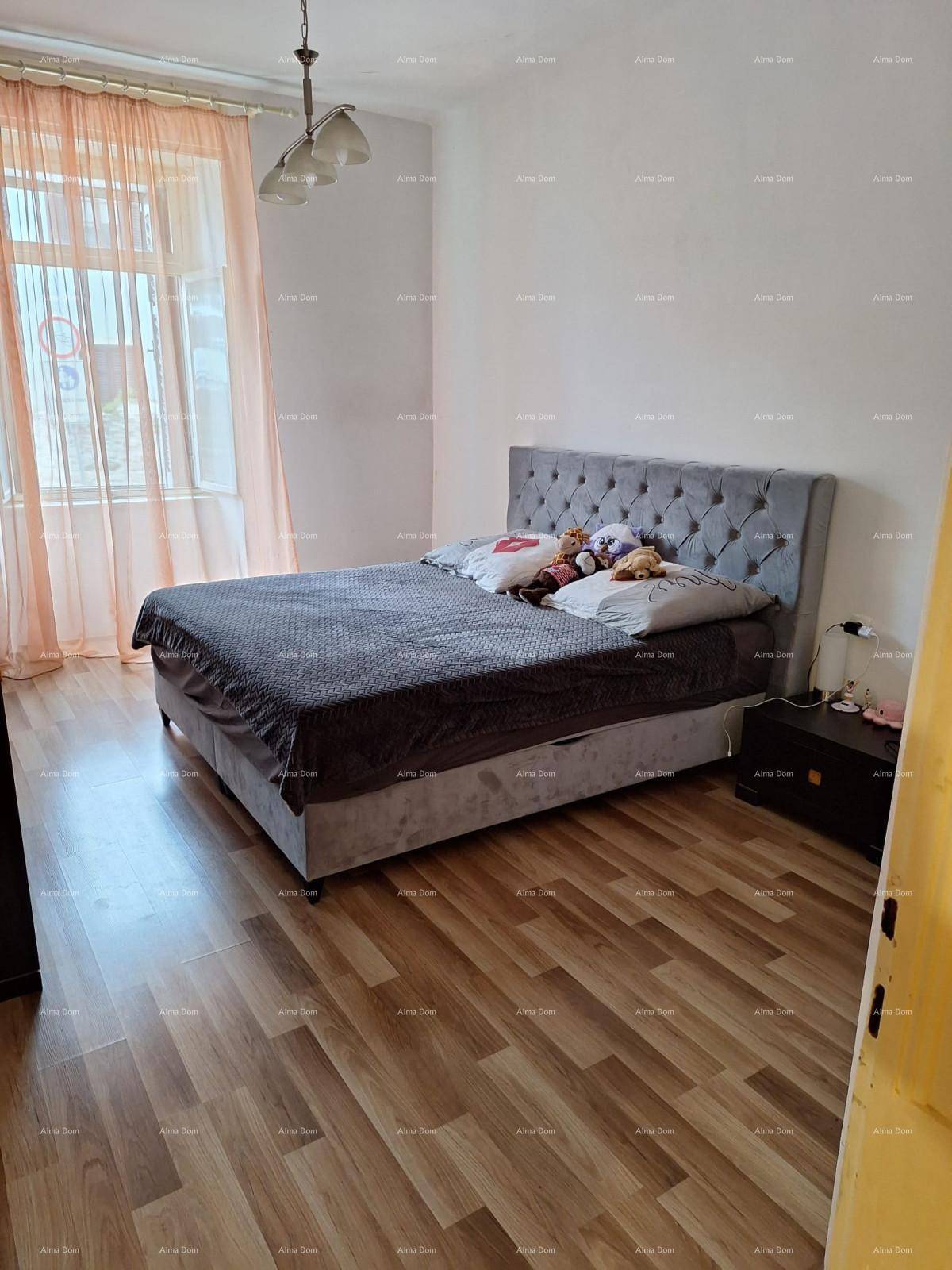 Schlafzimmer mit großem gepolstertem Bett, Holzboden und Fenster.
