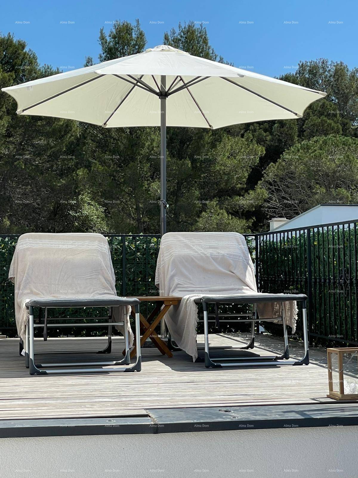 Gemütliche Dachterrasse mit Sonnenschirm und Sitzgelegenheiten, umgeben von Bäumen.